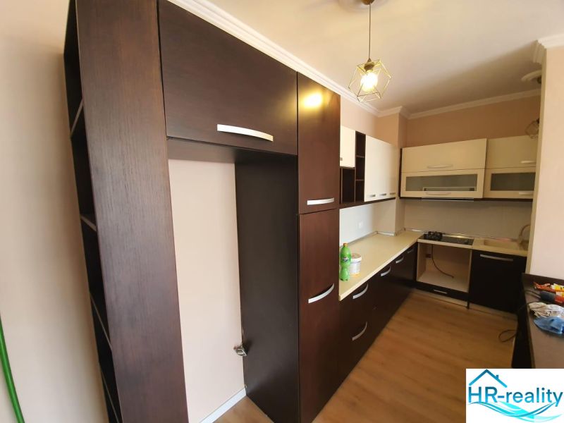 Küche in der Ferienwohnung, dominiert von dunklen Schränken und einem Boden mit Holzdekor.
