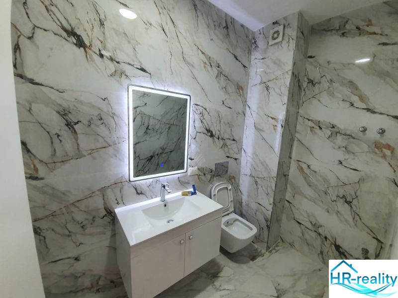 Badezimmer in der Ferienwohnung mit Marmordekor und Spiegel mit LED-Beleuchtung.