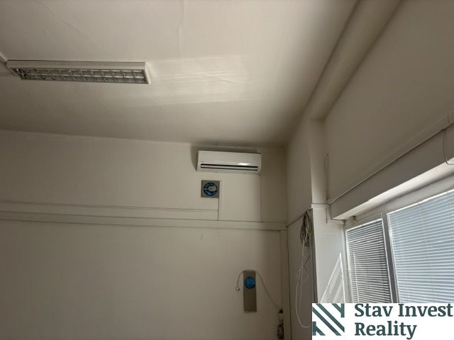 Deckenklimaanlage in Geschäftsräumen mit weißen Jalousien an den Fenstern.