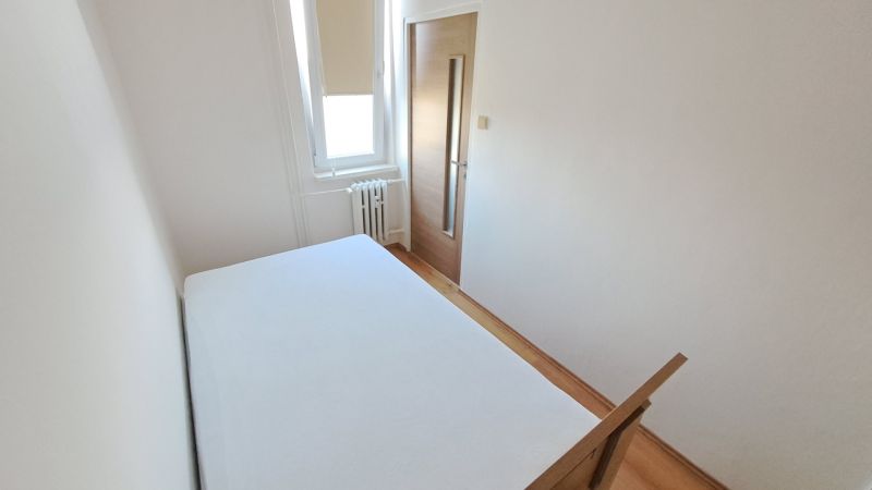 Schlafzimmer mit weißen Wänden und einem Boden in Holzoptik in einer 2-Zimmer-Wohnung.