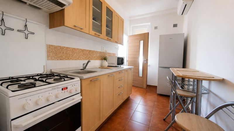 Küche in einer 2-Zimmer-Wohnung mit Holzschränken, Herd und Esstisch.