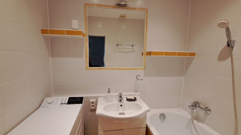 Badezimmer mit Waschbecken, Spiegel, Waschmaschine und Badewanne in einer 2-Zimmer-Wohnung.