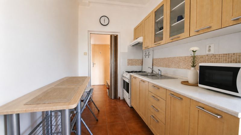 Küche in einer 2-Zimmer-Wohnung mit Holzschränken und Mikrowelle.