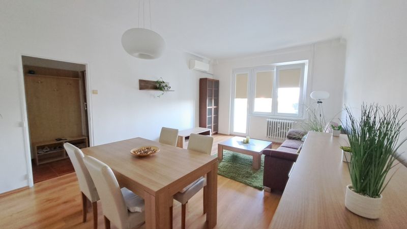 Wohnzimmer in einer 2-Zimmer-Wohnung mit Holzboden und Esstisch.
