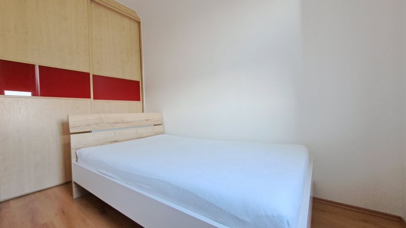 Schlafzimmer mit Bett und Einbauschrank, 2-Zimmer-Wohnung, Boden mit Holzdekor.