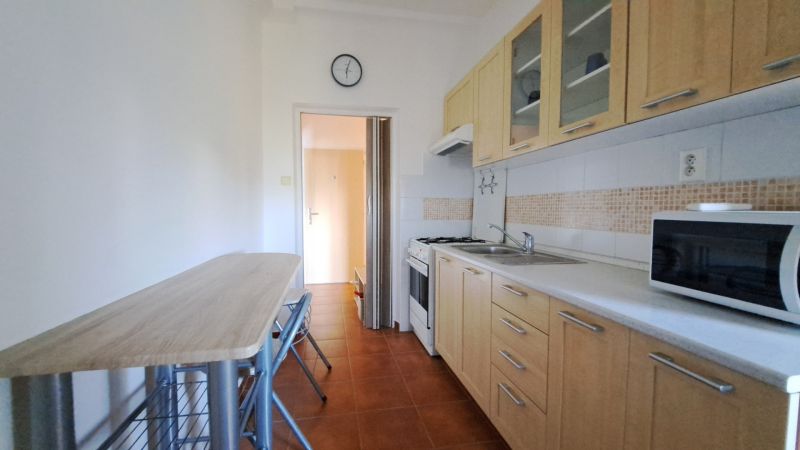 Küche in einer 2-Zimmer-Wohnung mit Esstisch und Geräten.