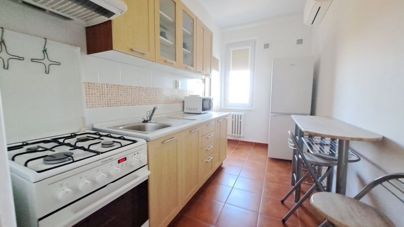 Küche in einer 2-Zimmer-Wohnung mit Gasherd, Spüle und Esstisch mit Stühlen.