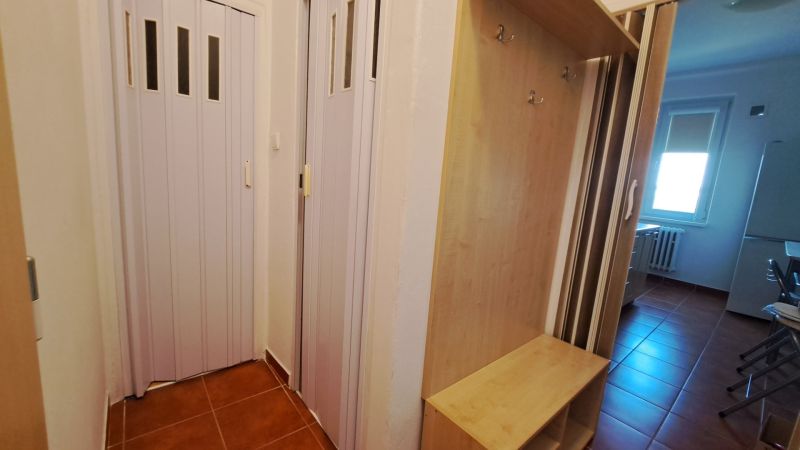 Eingang mit braunen Fliesen, Kleiderschrank und Schiebetüren in einer 2-Zimmer-Wohnung.