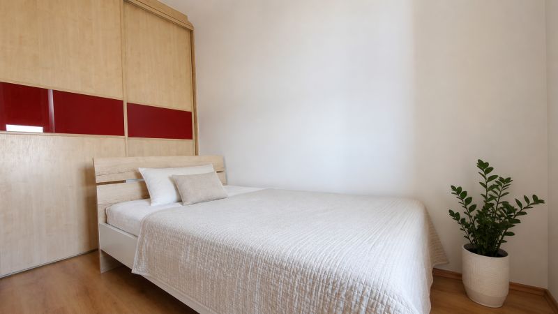 Schlafzimmer in einer 2-Zimmer-Wohnung mit Holzboden und Einbauschrank.