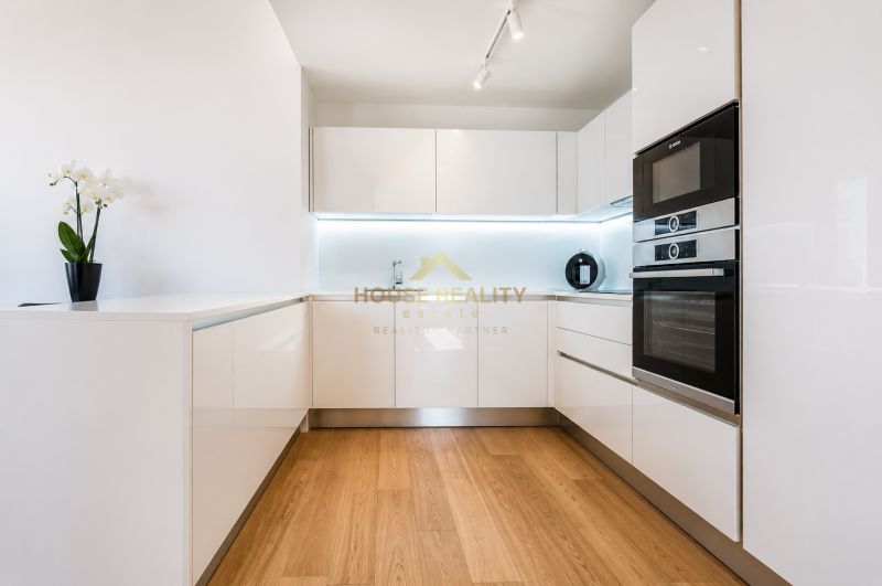 Küche in einer 3-Zimmer-Wohnung mit weißen Schränken und einem Boden in Holzoptik.