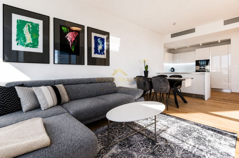 Wohnzimmer in einer 3-Zimmer-Wohnung mit einem bequemen Sofa, dekorativen Bildern und heller Einrichtung.