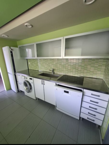 Küche in einer 3-Zimmer-Wohnung mit weißen Schränken und grünen Fliesen.