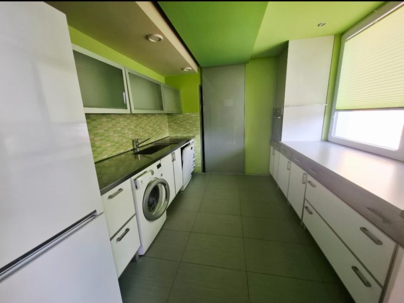 Küche in einer 3-Zimmer-Wohnung mit Waschmaschine, weißen Möbeln und grünen Wänden.