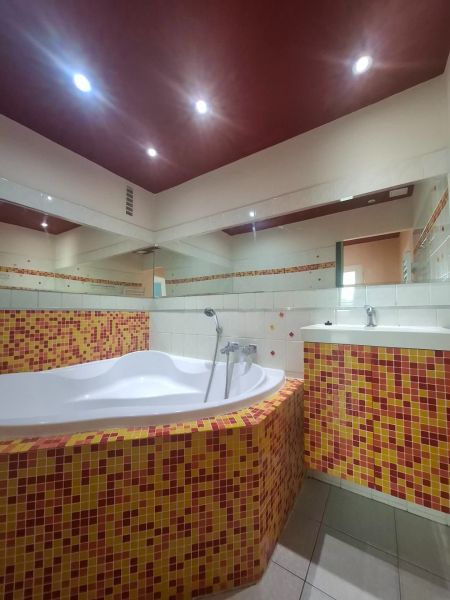 Badezimmer mit einer mit bunten Mosaikfliesen verkleideten Badewanne in einer 3-Zimmer-Wohnung.