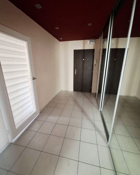 Flur in einer 3-Zimmer-Wohnung mit Fliesen, einem Spiegelschrank und dunklen Türen.