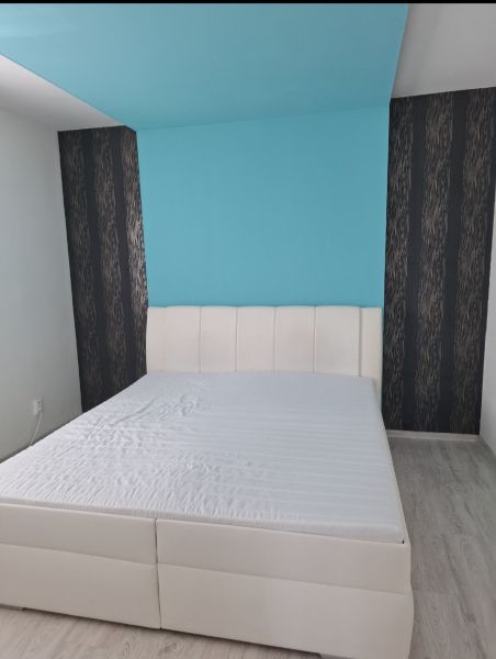 Helles Schlafzimmer mit weißem Bett und blauer Wand in einer 3-Zimmer-Wohnung.