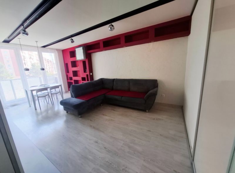 Wohnzimmer in einer 3-Zimmer-Wohnung mit Ecksofa, Esstisch und Boden in Holzoptik.