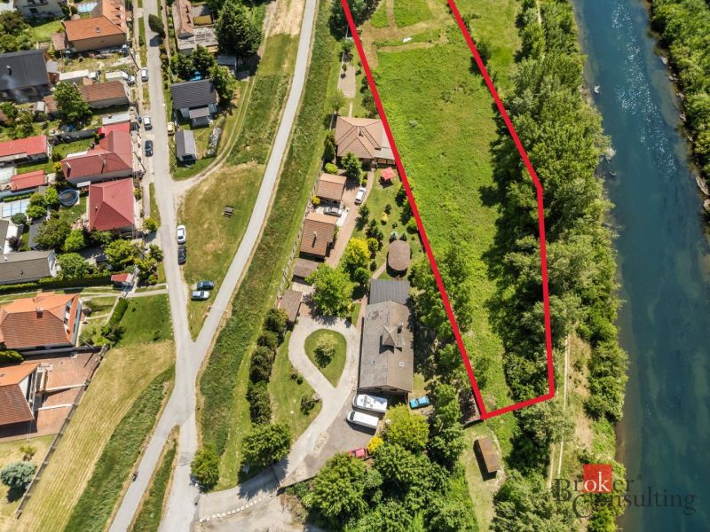 Freizeitgrundstücke in Hamuliakovo am Fluss, umgeben von Grün und Häusern.