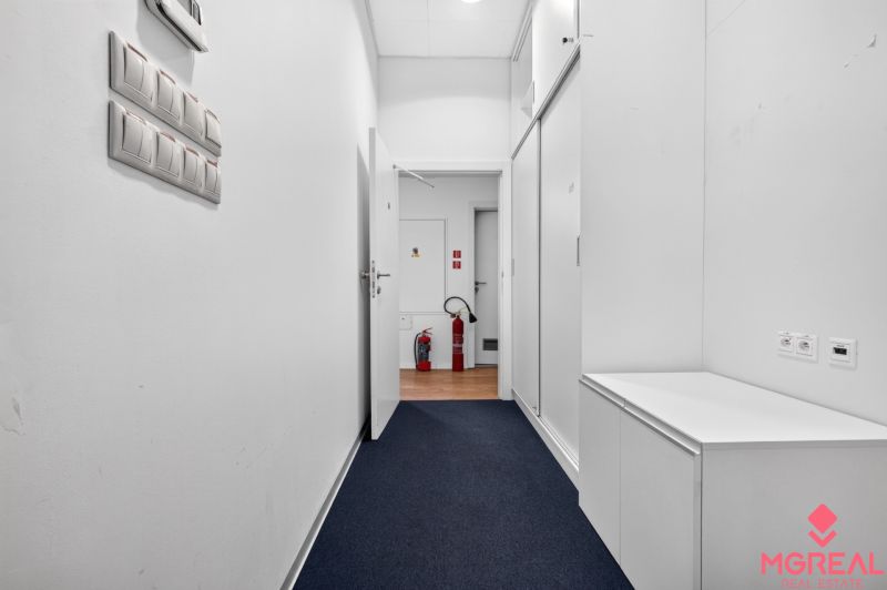 Ein Flur mit weißen Wänden und einem Boden in Holzoptik in Geschäftsräumen.
