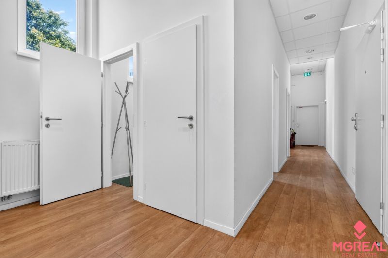 Innenraum von Geschäftsräumen mit weißen Wänden, Holzboden und Kleiderschrank.