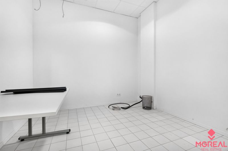 Ein leerer Innenraum mit weißen Wänden, einem Tisch und weißen Fliesen in Geschäftsräumen.