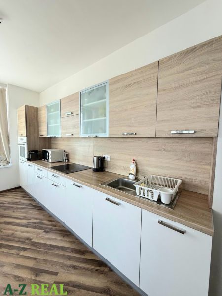 Küchenzeile mit weißen Schränken und Bodenbelag in Holzoptik in einer 3-Zimmer-Wohnung.