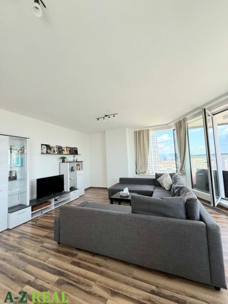 Wohnzimmer mit Holzboden, Sofa und Fernseher in einer 3-Zimmer-Wohnung.