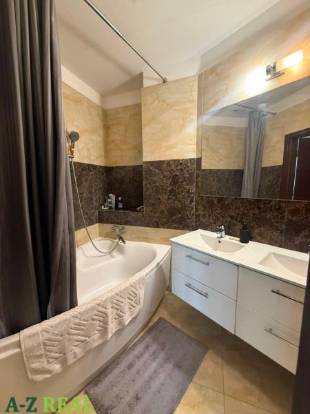 Badezimmer mit Badewanne, Waschbecken und eleganten Fliesen in einer 3-Zimmer-Wohnung.