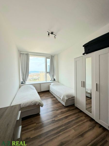Ein Zimmer mit zwei Betten und einem Schrank, Holzboden in einer 3-Zimmer-Wohnung.