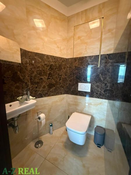 Toilette mit Waschbecken in einer 3-Zimmer-Wohnung, Steinverkleidung und Boden.
