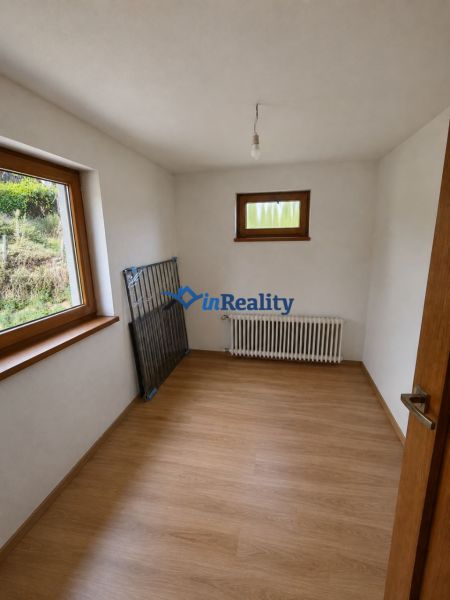 Ein Zimmer in einem Einfamilienhaus mit einem Heizkörper und einem Boden in Holzoptik.