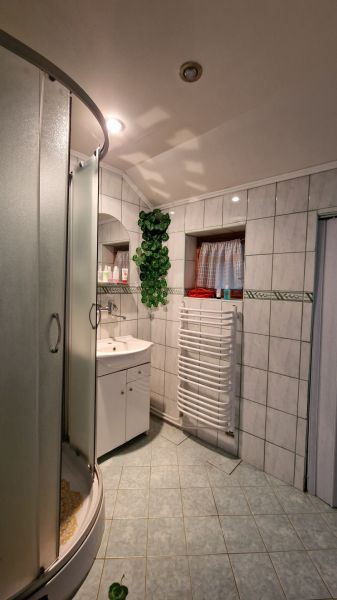 Badezimmer mit Fliesen, Duschkabine, Waschbecken und Heizkörper, eingerichtet in einem Einfamilienhaus.
