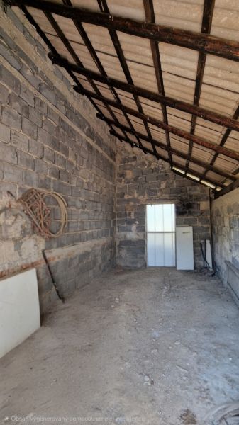 Ein Schuppen mit einem schrägen Blechdach und Betonwänden, der sich in einem Einfamilienhaus befindet.