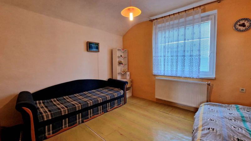 Wohnzimmer im Einfamilienhaus mit Sofa, Regal und Vorhang am Fenster.