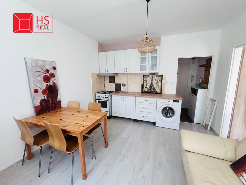 Küche in einer Einzimmerwohnung mit Holztisch, Stühlen und Boden mit Holzdekor.