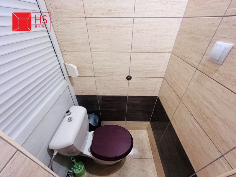 Toilette mit Fliesen in einer Einzimmerwohnung, helle und dunkle Fliesen an den Wänden.