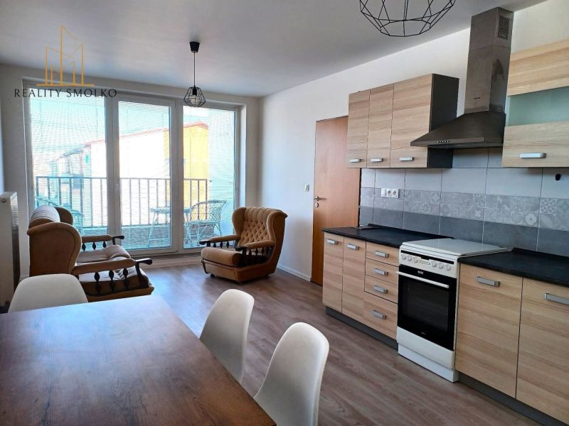Wohnzimmer mit Sofas, Küchenzeile und Holzboden in einer Zweizimmerwohnung.