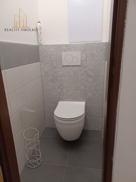 Toilette in einer 2-Zimmer-Wohnung mit dekorativen Wandverkleidungen und grauem Boden.