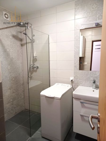 Badezimmer in einer 2-Zimmer-Wohnung mit Waschmaschine, Duschkabine und Waschbecken.