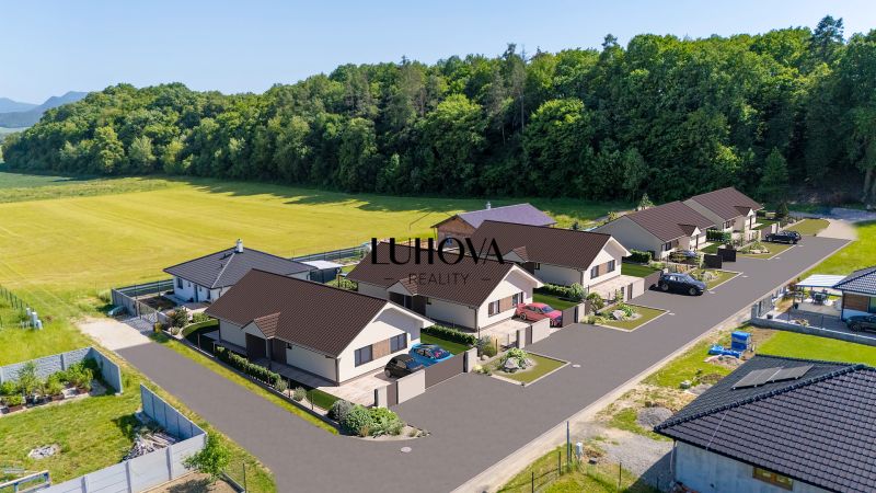 Einfamilienhäuser in der Straße Tuchyňa im Dorf Tuchyňa, umgeben von Wald und Feld.