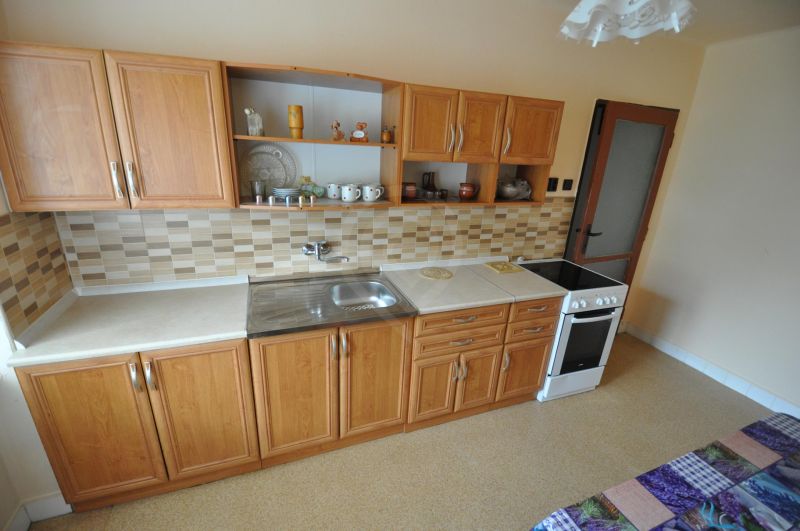 Küche mit Holzschränken und Mosaikfliesen in einer Zweizimmerwohnung.