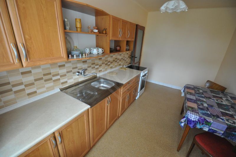 Küche in einer 2-Zimmer-Wohnung mit Holzschränken und Fliesenverkleidung.