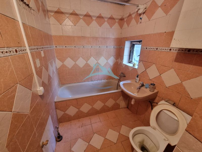 Badezimmer mit Fliesen und Verkleidung, Badewanne, Waschbecken und Toilette im Einfamilienhaus.