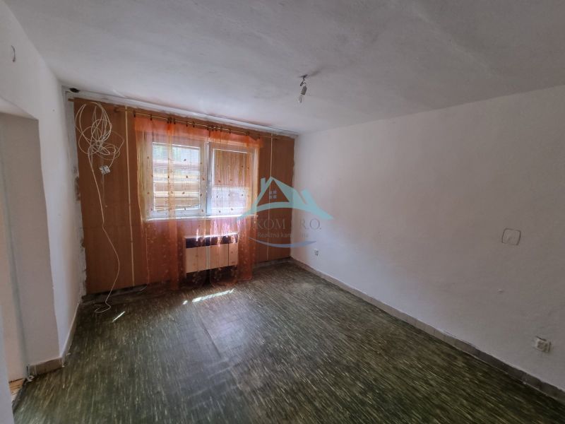 Ein Zimmer in einem Einfamilienhaus mit Boden und Fenstern mit Vorhängen.