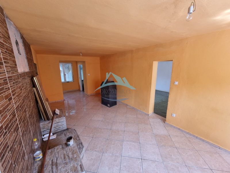 Wohnzimmer in einem Einfamilienhaus mit orangefarbenen Wänden und Fliesenboden.