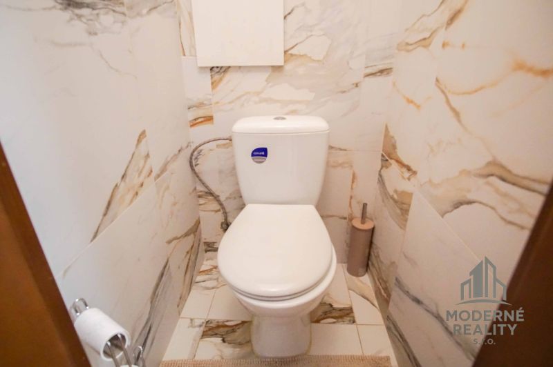 Toilette im Badezimmer mit Marmorfurnier in einer 2-Zimmer-Wohnung.