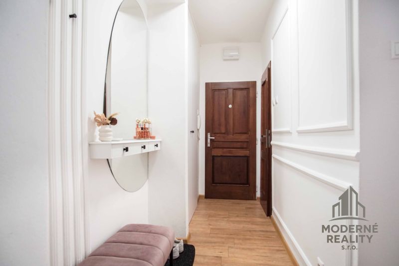 Der Flur einer 2-Zimmer-Wohnung mit einem Boden in Holzoptik und einem Spiegel an der Wand.