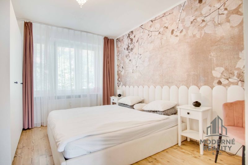 Schlafzimmer in einer 2-Zimmer-Wohnung mit Holzboden und dezenter Tapete.