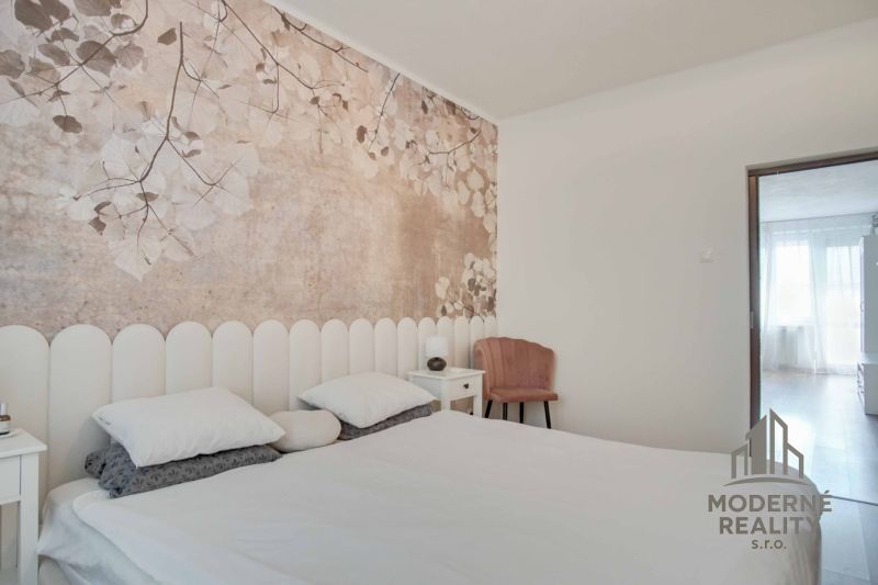 Schlafzimmer in einer 2-Zimmer-Wohnung mit Wanddekoration aus Blumen und hellen Möbeln.