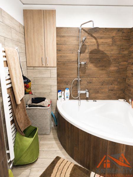 Badezimmer in einer 3-Zimmer-Wohnung mit Badewanne und Fliesendekor in Holzoptik.